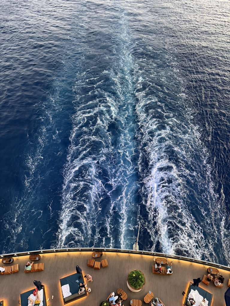 A cruise ship's white wake trailing across deep blue ocean